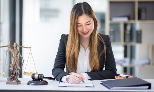 Young woman smiling at her desk in a legal office after finding her dream job through Legal Career Connect.