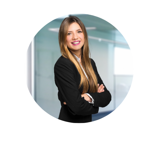 Confident young professional woman smiling in an office setting with her arms folded.